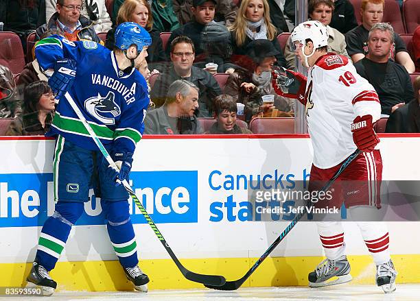 Willie Mitchell of the Vancouver Canucks looks on as Shane Doan of the Phoenix Coyotes handles the puck with his glove during their game at General...