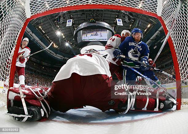 Daniel Sedin of the Vancouver Canucks is checked off the puck by Kurt Sauer of the Phoenix Coyotes as Ilya Bryzgalov of the Coyotes makes a save...