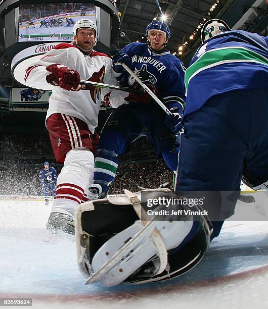 Todd Fedoruk of the Phoenix Coyotes and Ryan Johnson of the Vancouver Canucks look for the rebound after Roberto Luongo of the Vancouver Canucks...