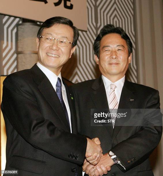 Japan's electronics giant Panasonic president Fumio Otsubo shakes hands with Sanyo Electric president Seiichiro Sano at a press conference in Osaka...