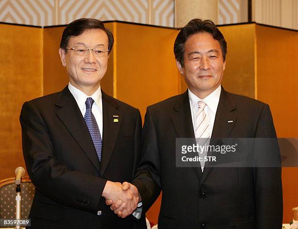 Japan's electronics giant Panasonic president Fumio Otsubo shakes hands with Sanyo Electric president Seiichiro Sano at a press conference in Osaka...