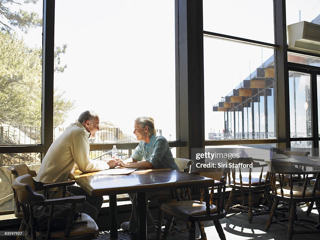 Madura pareja sosteniendo las manos en el restaurante