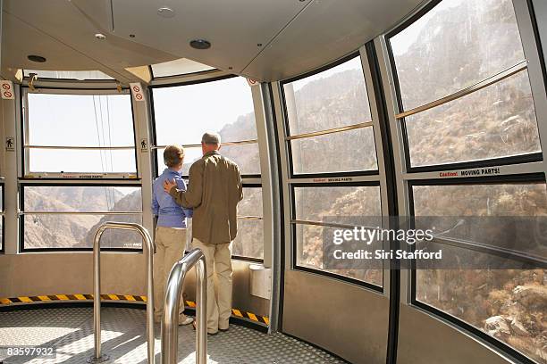 älteres paar blick aus fenster mit der straßenbahn - seilbahn stock-fotos und bilder