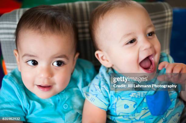 12 month old twins sit together at home - fraternal twin stock pictures, royalty-free photos & images