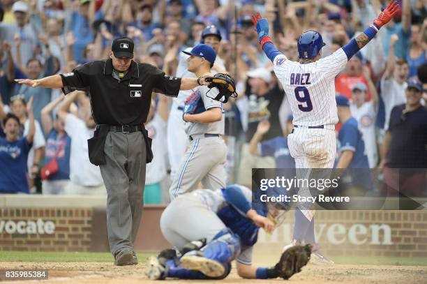 Javier Baez of the Chicago Cubs beats a tag at home plate by Raffy Lopez of the Toronto Blue Jays to score the winning run during the tenth inning at...