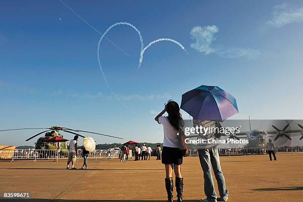 People watch the Indian Air Force Surya Kiran Aerobatics Team conduct sky manoeuvres at the 7th China International Aviation and Aerospace Exhibition...