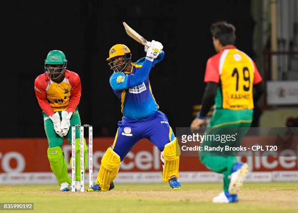 In this handout image provided by CPL T20, Dwayne Smith of Barbados Tridents hits 4 as Chadwick Walton and Rashid Khan of Guyana Amazon Warriors...