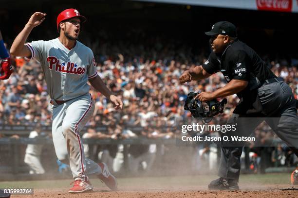 Cameron Perkins of the Philadelphia Phillies reacts after getting called out by umpire Adrian Johnson on a tag at home plate by Buster Posey of the...