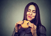woman eating a big hamburger, isolated on gray background