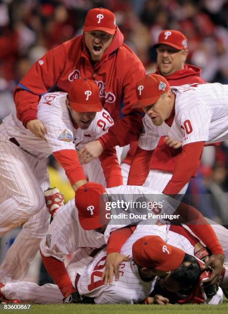 Chase Utley, Ryan Howard and Geoff Jenkins of the Philadelphia Phillies pile on top of closing pitcher Brad Lidge and catcher Carlos Ruiz after they...