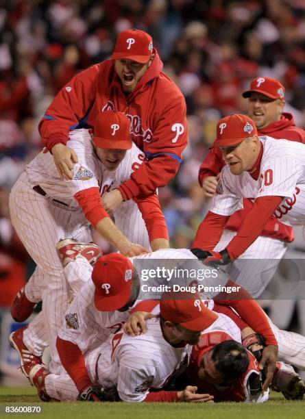 Chase Utley, Ryan Howard and Geoff Jenkins of the Philadelphia Phillies pile on top of closing pitcher Brad Lidge and catcher Carlos Ruiz after they...