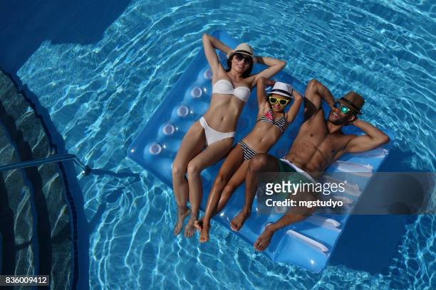 happy family lying to pool raft in swimming pool - black people in bathing suits stock pictures, royalty-free photos & images