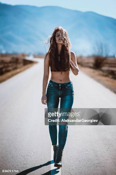 attractive female walking on empty road in the middle of nowhere - highway exit sign stock pictures, royalty-free photos & images
