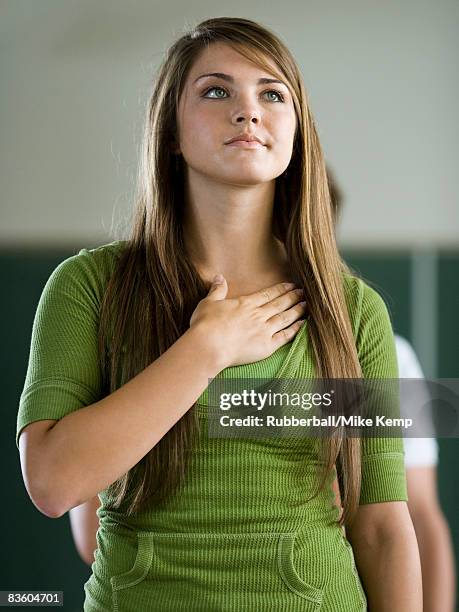 young woman in a classroom with hand over heart. - amerikanischer treueschwur stock-fotos und bilder