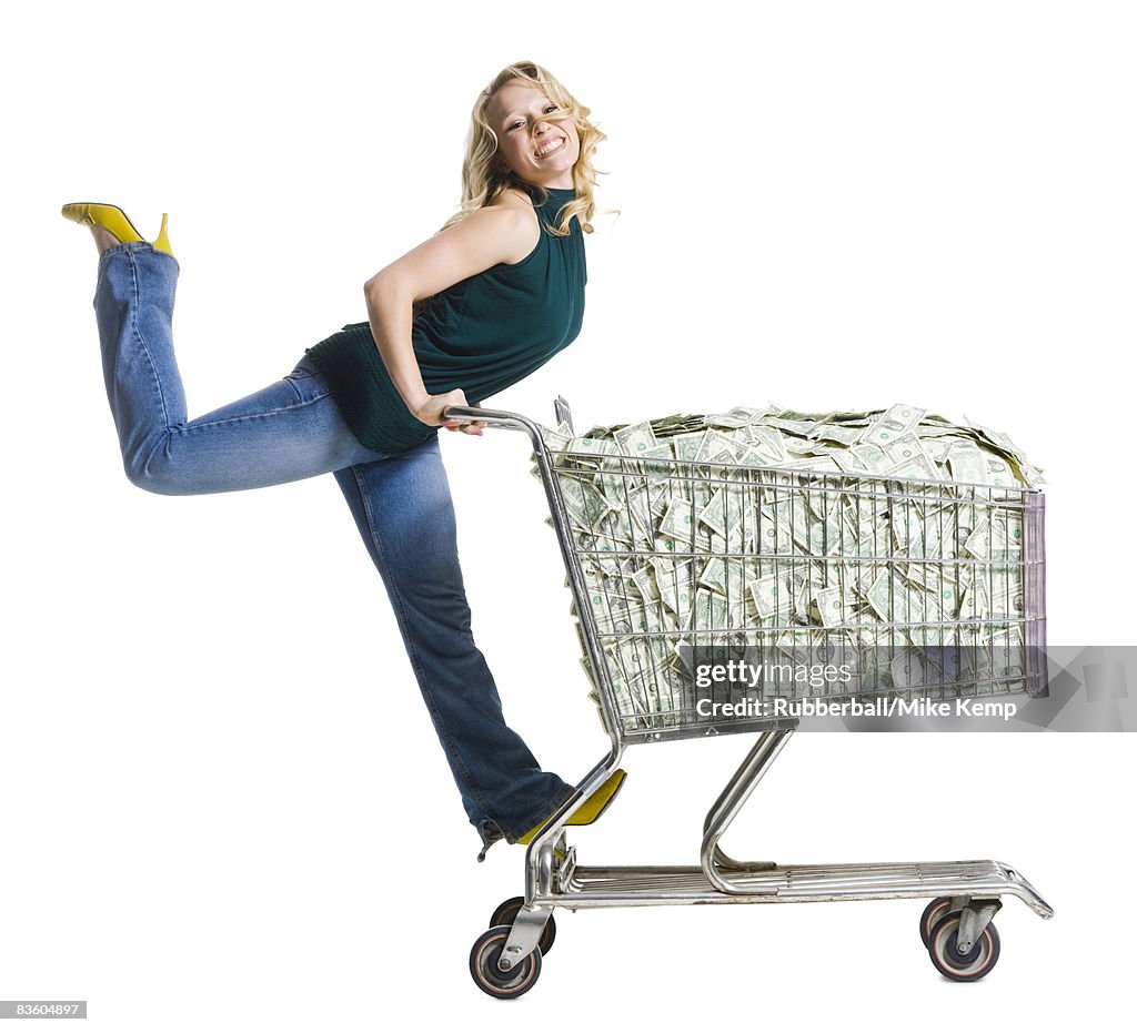 Woman with a shopping cart full of money