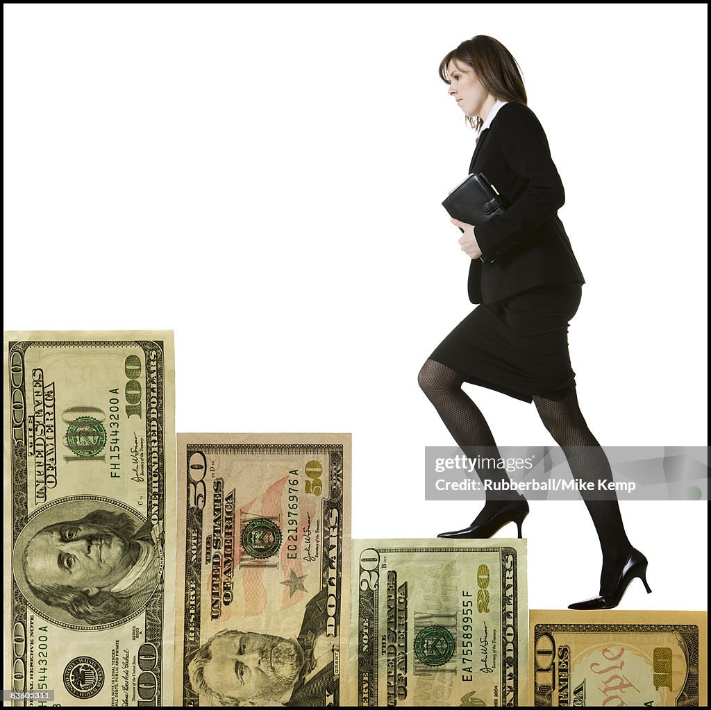 Businessperson climbing a staircase of money