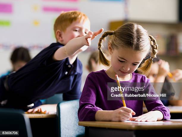 boy teasing girl - naughty kids in classroom 個照片及圖片檔