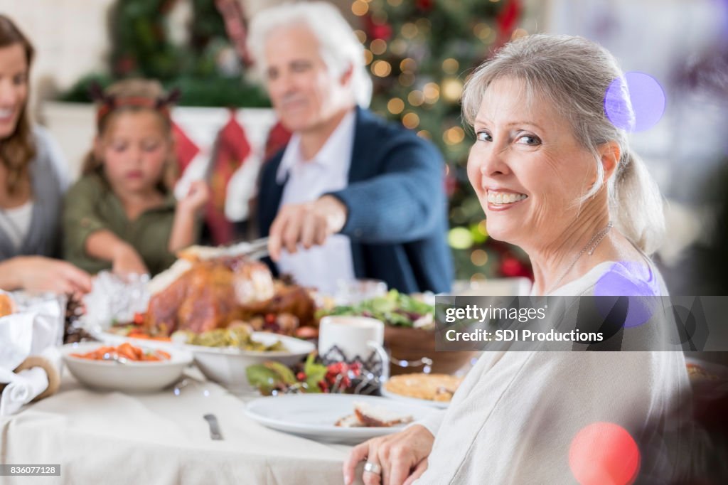Senior woman smile for camera at family Christmas dinner