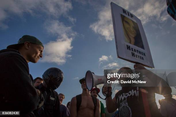 Demonstrators argue with a counter demonstrator holding a sign in memorial to 32-year-old Heather Heyer, who killed when a man rammed his car into a...