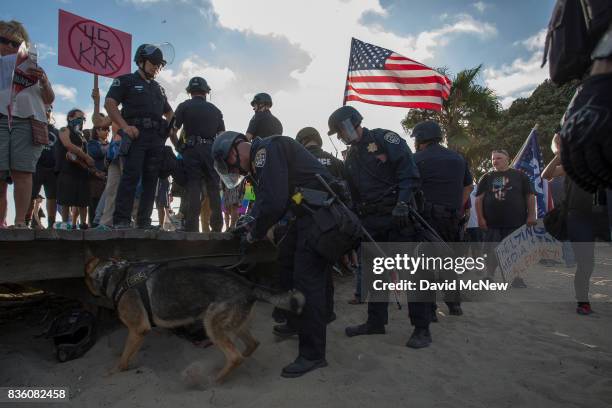 Police use a bomb-sniffing dog to check on packs owned by demonstrators at an 'America First' demonstration on August 20, 2017 in Laguna Beach,...