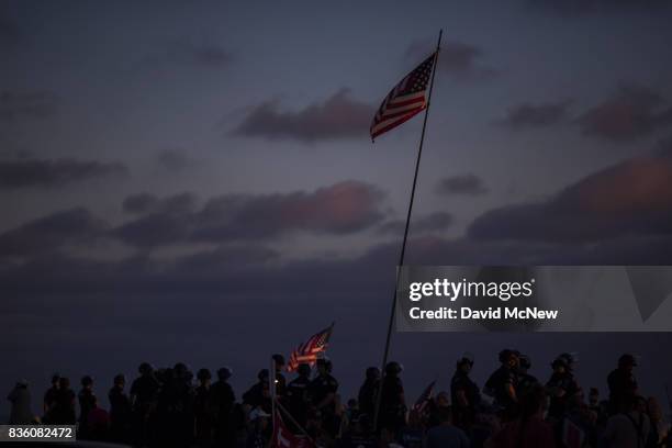 Flags are waved as police form a line to keep demonstrators and counter demonstrators apart at an 'America First' demonstration on August 20, 2017 in...