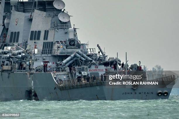 The guided-missile destroyer USS John S. McCain, with a hole on its portside after a collision with an oil tanker, makes its way to Changi naval base...