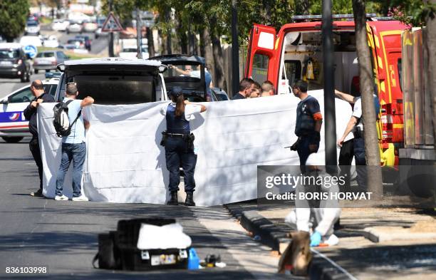 White sheet is erected as a body of a victim is evacuated to a waiting ambulance while French forensic police officer search the site following a car...