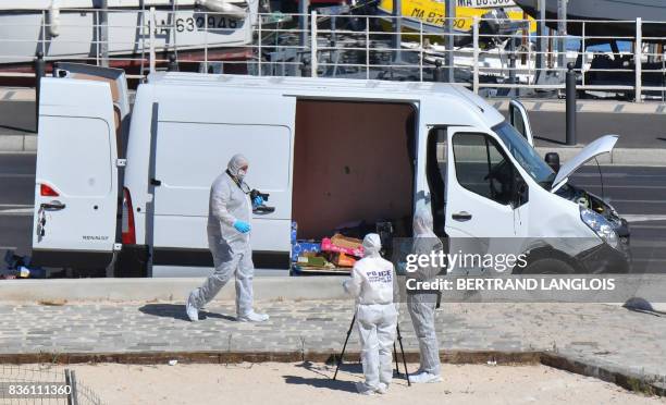 French forensic police officers take images as they search a vehicle following a car crash in the southern Mediterranean city of Marseille on August...