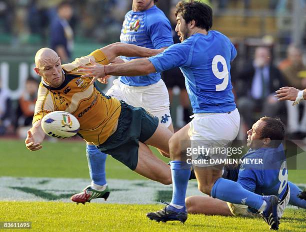 Australia's centre and captain Stirling Mortlock sends the ball as he is tackled by Italy's Sergio Parisse and Italy's scrum-half Pablo Canavosio...