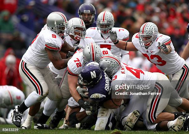 Stephan Simmons of the Northwestern Wildcats is tackled by Nate Williams and Dexter Larimore of the Ohio State Buckeyes at Ryan Stadium on November...
