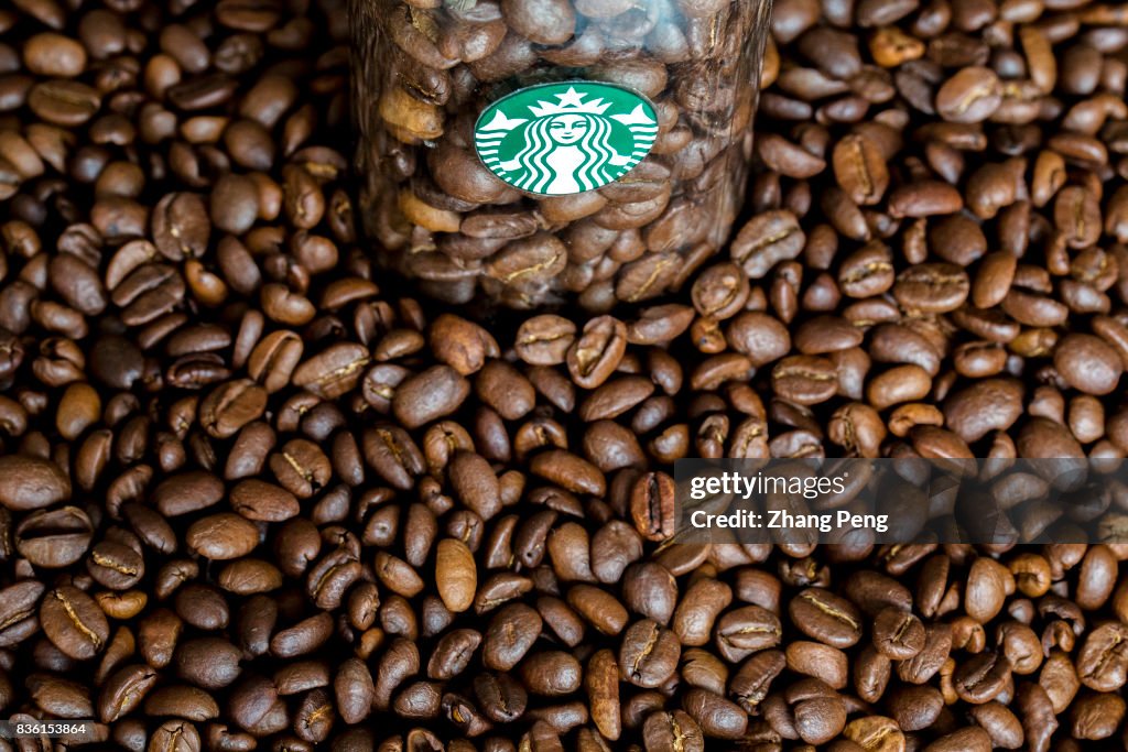 Coffee beans and Starbucks logo, arranged for photography.