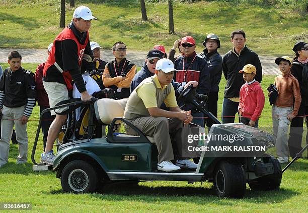 Anthony Kim of the US is driven away from the 11th hole by an official after being disqualified from the event due to a club violation in the third...