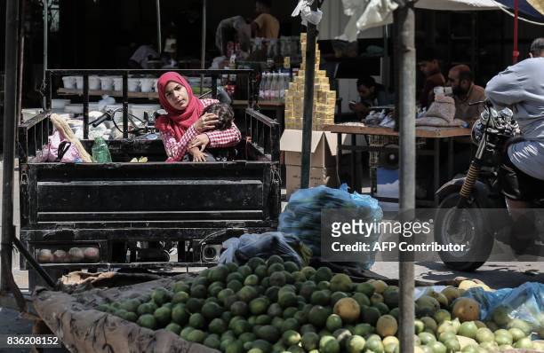 Palestinian youth and her little brother wait for their father to finish shopping at a popular market in Rafah in the Southern Gaza Strip on August...