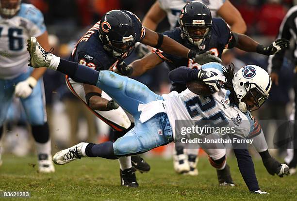 Chris Johnson of the Tennessee Titans goes airborne as he runs the ball against Adewale Ogunleye and Nick Roach of the Chicago Bears at Soldier Field...