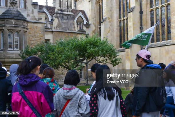 Chinese tourists stand in front of Isaac Newton's apple tree at Trinity College, part of the University of Cambridge on August 19, 2017 in Cambridge,...