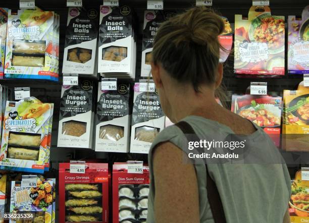 Woman inspects Insect Burgers, which are seen on sale, in Switzerland's second biggest supermarket chain in Geneva, Switzerland on August 21, 2017....