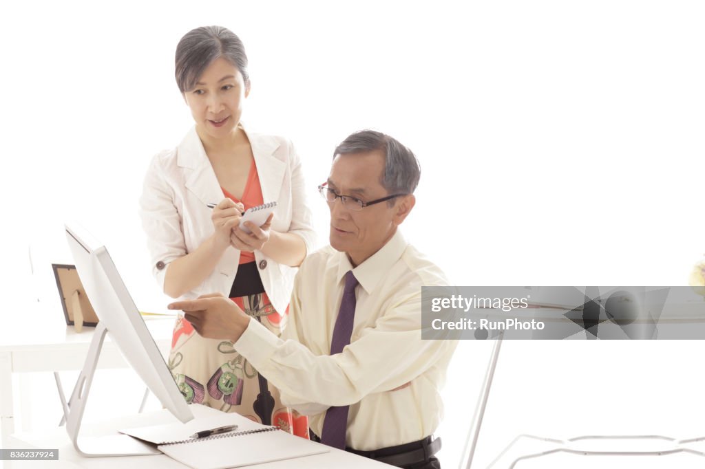 Middle-aged woman who records on a memo paper while watching a computer