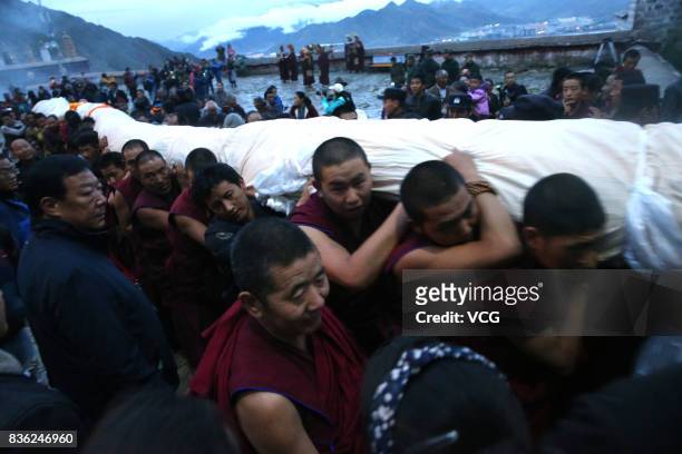 Tibetan buddhist monks carry a large thangka to display during the Sho Dun Festival at Drepung Monastery on August 21, 2017 in Lhasa, China. The Sho...