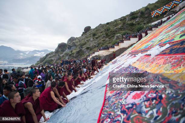 Local residents and tourists worship a large thangka during the Sho Dun Festival at Drepung Monastery on August 21, 2017 in Lhasa, China. The Sho Dun...