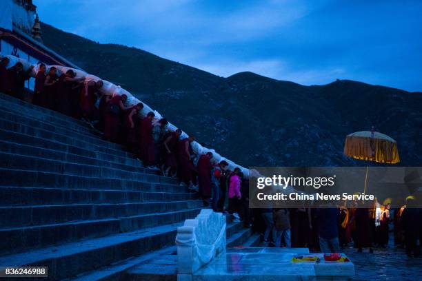 Tibetan buddhist monks carry a large thangka to display during the Sho Dun Festival at Drepung Monastery on August 21, 2017 in Lhasa, China. The Sho...