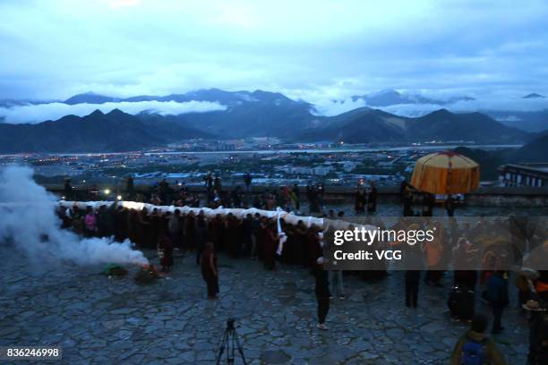 Tibetan buddhist monks carry a large thangka to display during the Sho Dun Festival at Drepung Monastery on August 21, 2017 in Lhasa, China. The Sho...