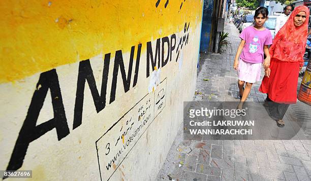 Maldivian pedestrians walk past electoral graffiti in the capital island of Male on November 10, 2008. Maldivian Democratic Party founder and...