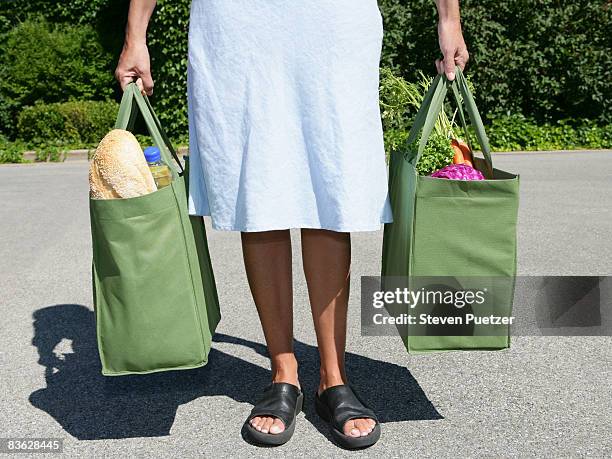 woman with reusable grocery bag in each hand - woman carrying tote bag fotografías e imágenes de stock