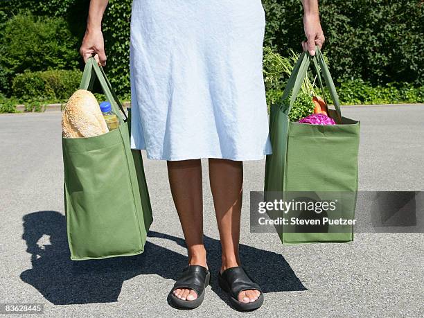 woman with reusable grocery bag in each hand - groceries bag stock pictures, royalty-free photos & images