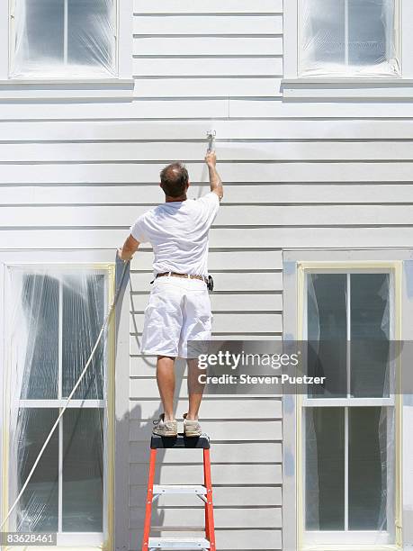 house painter standing on ladder painting exterior - spray gun stock pictures, royalty-free photos & images