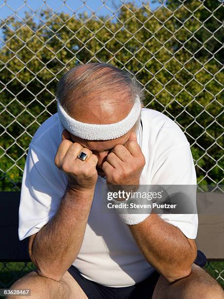 senior tennis player holding head in hands  - headband stock-fotos und bilder