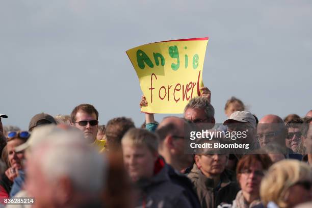 An attendee holds a sign that reads "Angie forever" during an election campaign stop in Saint Peter-Ording, Germany, on Monday, Aug. 21, 2017. Merkel...