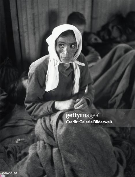 Gypsy woman suffering from typhus at Bergen-Belsen concentration camp waits with other gypsies for medical treatment, April 1945. 60,000 civilian...