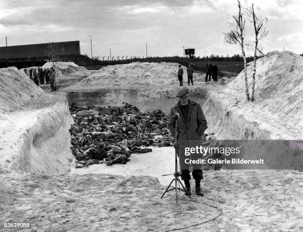 Reporter stands in front of a mass grave at Bergen-Belsen concentration camp, after its liberation by the British army, April 1945. 60,000 civilian...