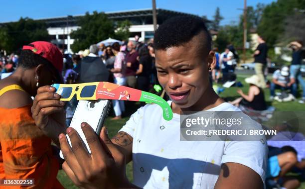 Asha Moore uses solar eclipse glasses and her iphone to show a friend from Canada on the phone the view of the partial solar eclipse from Beckman...